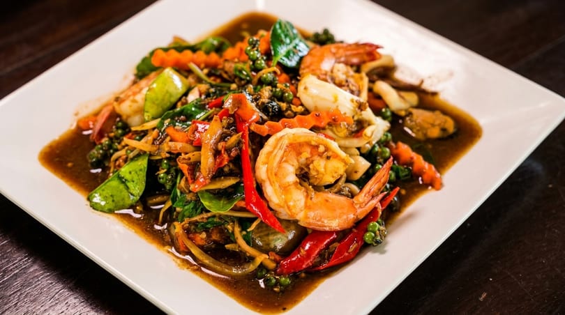 Spicy Thai stir-fried seafood with shrimp, squid, mussels, green peppercorns, and red chilies.
